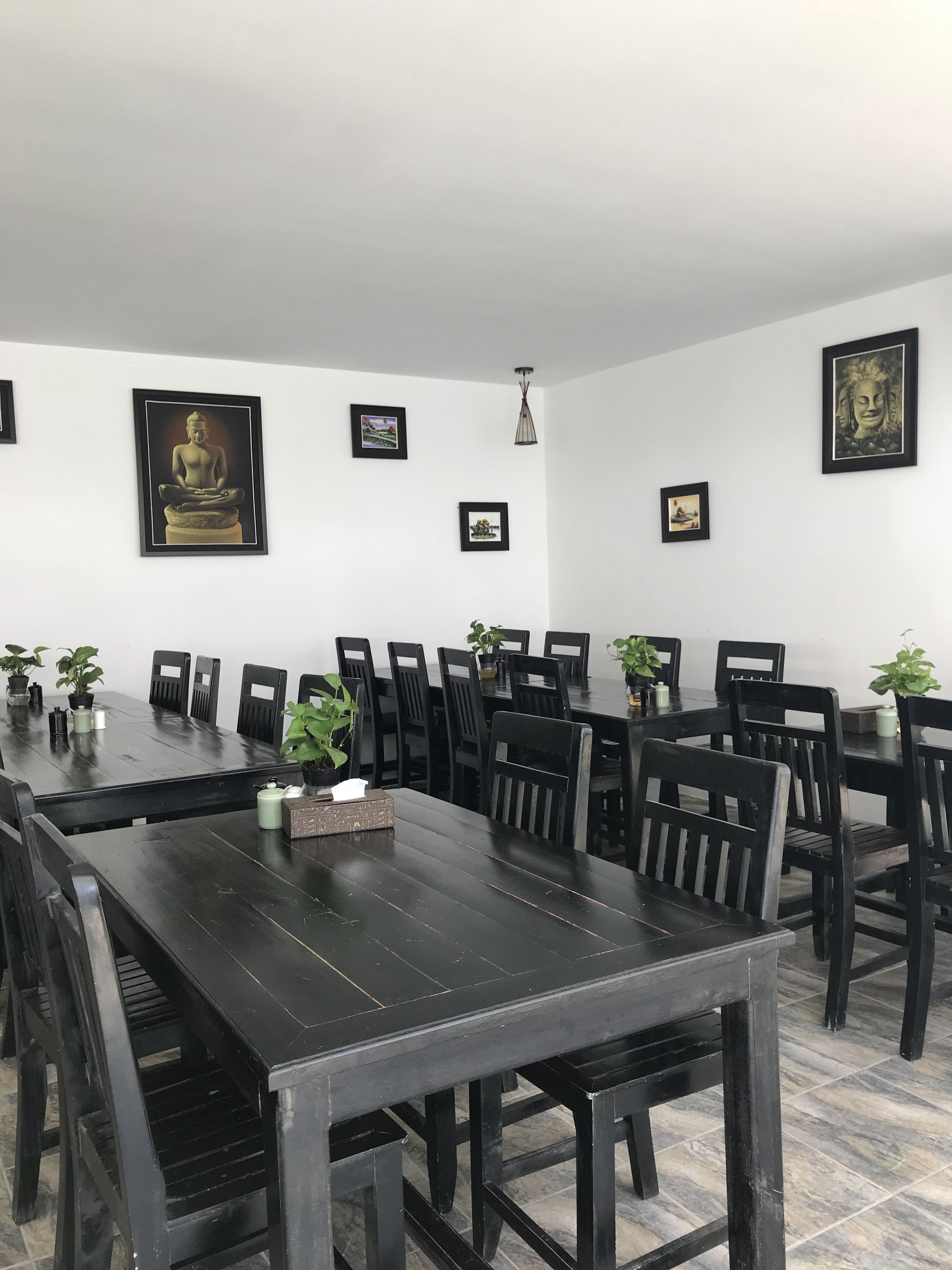 Une salle de conférence avec une longue table et des chaises, des œuvres d’art encadrées aux murs et des plantes en pot.