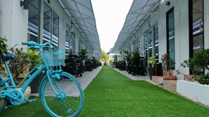 A pathway lined with tables and chairs, leading to a building with a glass facade. - Good Time Boutique Hotel (Sihanoukville)