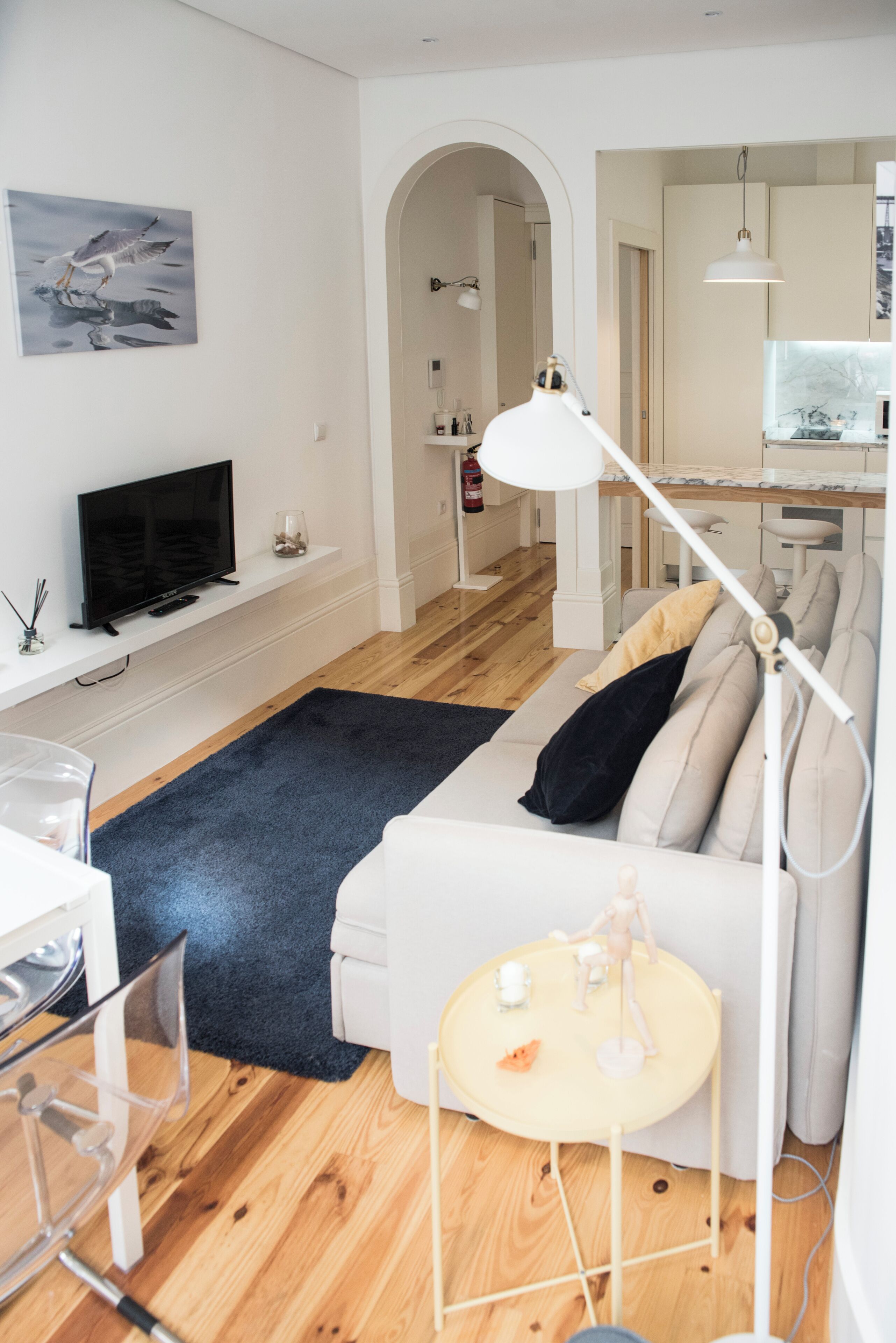 A modern living room with a sofa, a small round table, a TV, and a lamp.