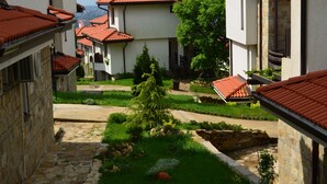 Un patio con senderos de piedra, un árbol en el centro y edificios con techos de tejas rojas.