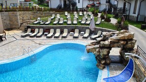Una piscina con sillas de descanso y un tobogán de agua.