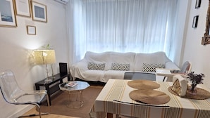 A modern living room with a sofa, coffee table, chairs, and a dining table.