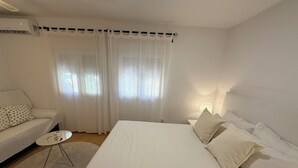 A hotel room with a bed, a sofa, a small table, and a lamp.