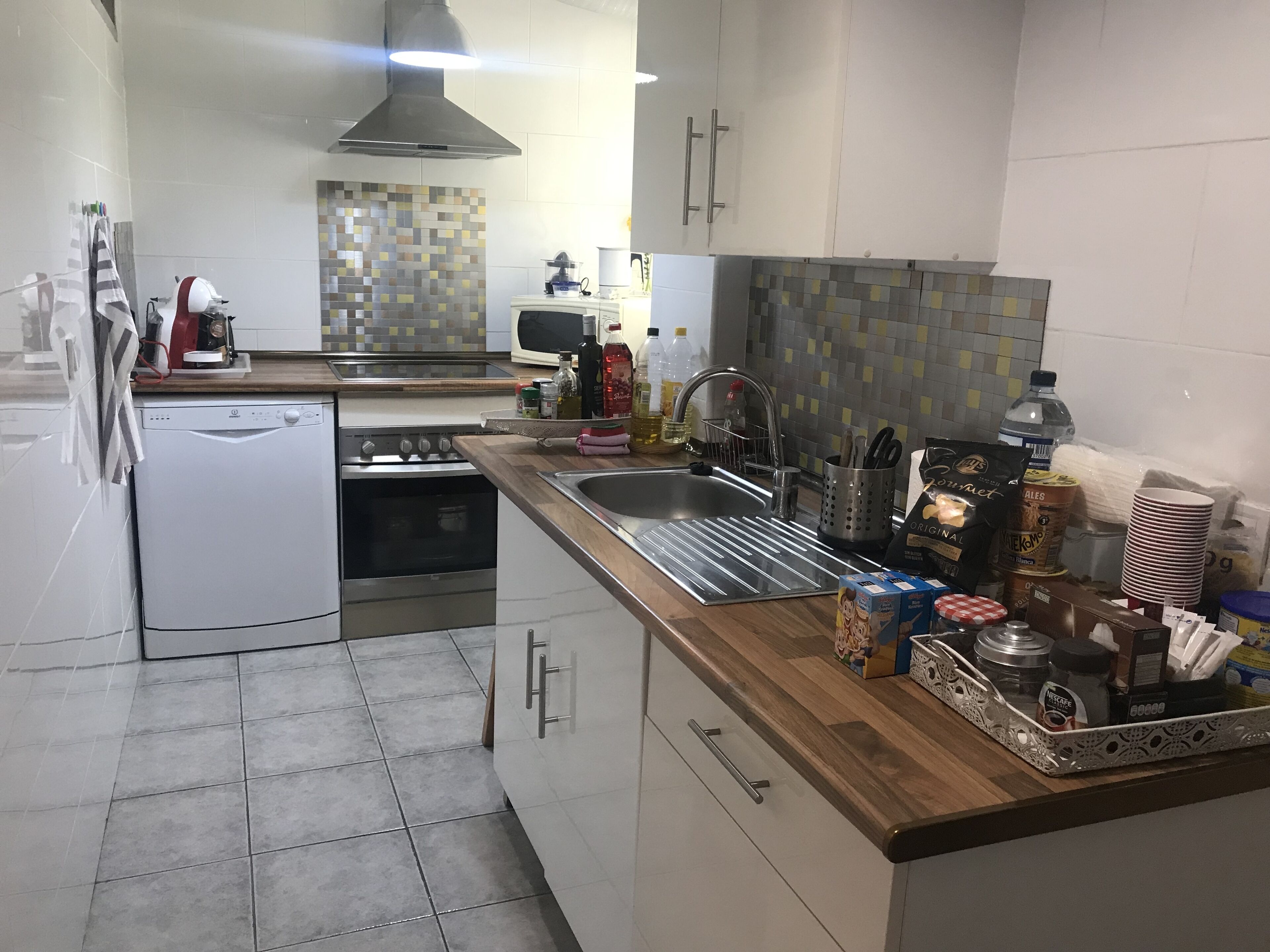 Een moderne keuken met witte kasten, een roestvrijstalen spoelbak en een houten aanrecht.