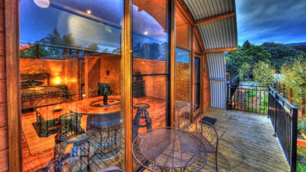 Um espaço amplo e interno com deck de madeira, uma mesa de jantar e cadeiras.