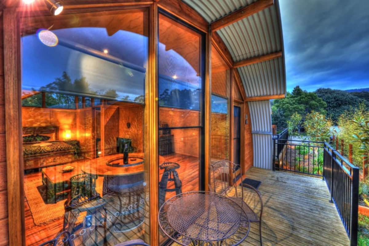 Un espacio interior amplio con una terraza de madera, una mesa de comedor y sillas.