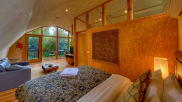 Un dormitorio con una cama grande, un sofá y un escritorio. Cuenta con ventanas amplias y vistas al exterior.