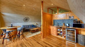 Um espaço compacto com piso de madeira, um sofá, uma mesa de jantar e uma cozinha com micro-ondas e pia.