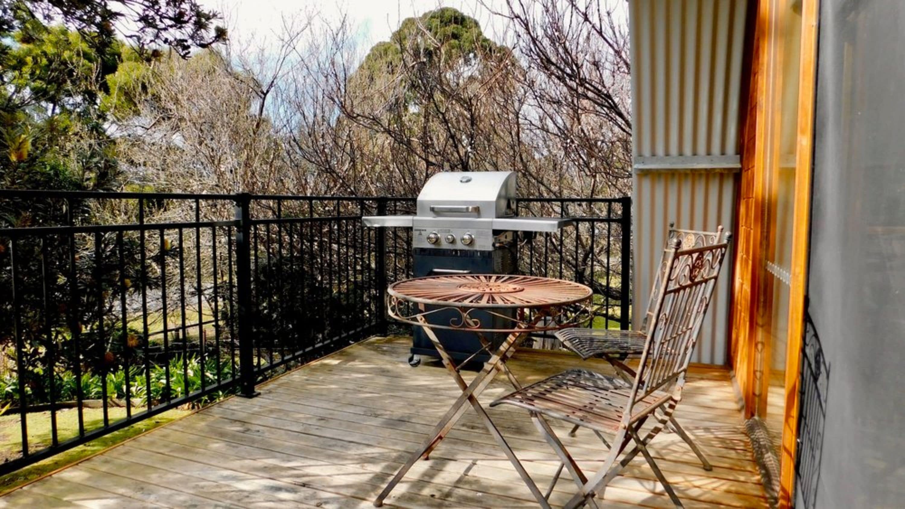 A balcony with a grill, a round table, and chairs.