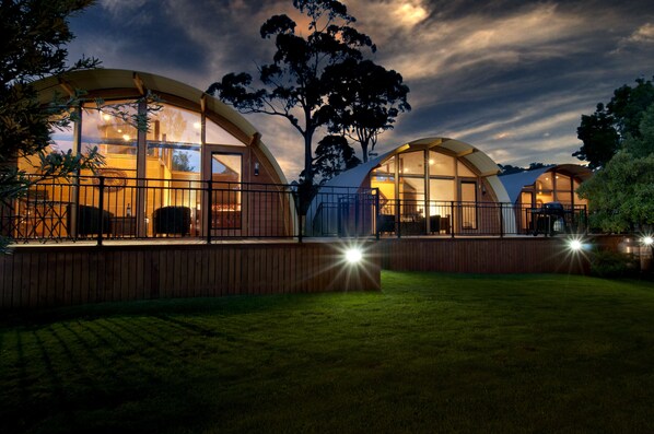 A modern, dome-shaped building with large windows and a wooden deck, surrounded by a well-maintained lawn. - 43 Degrees Bruny Island (Adventure Bay)