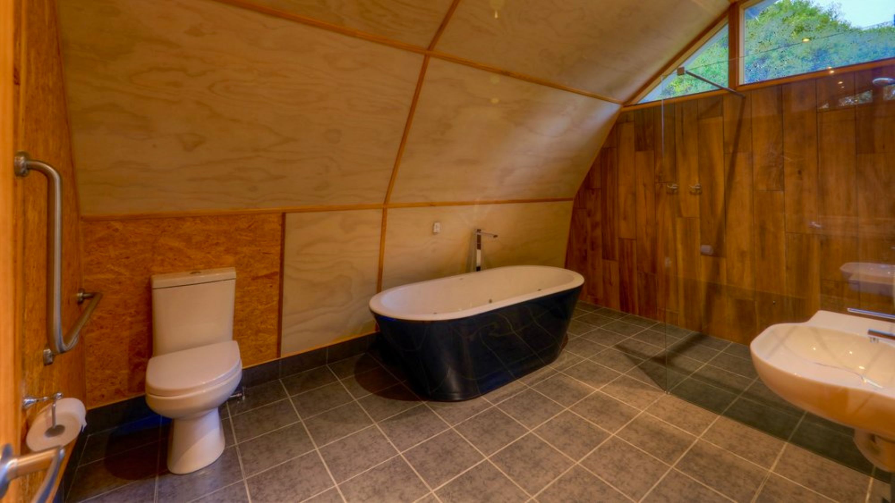 A compact bathroom with a toilet, a freestanding bathtub, and a sink.