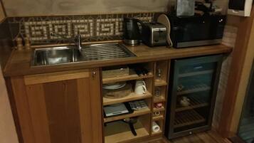 A compact kitchen with a sink, toaster, kettle, and a small refrigerator.
