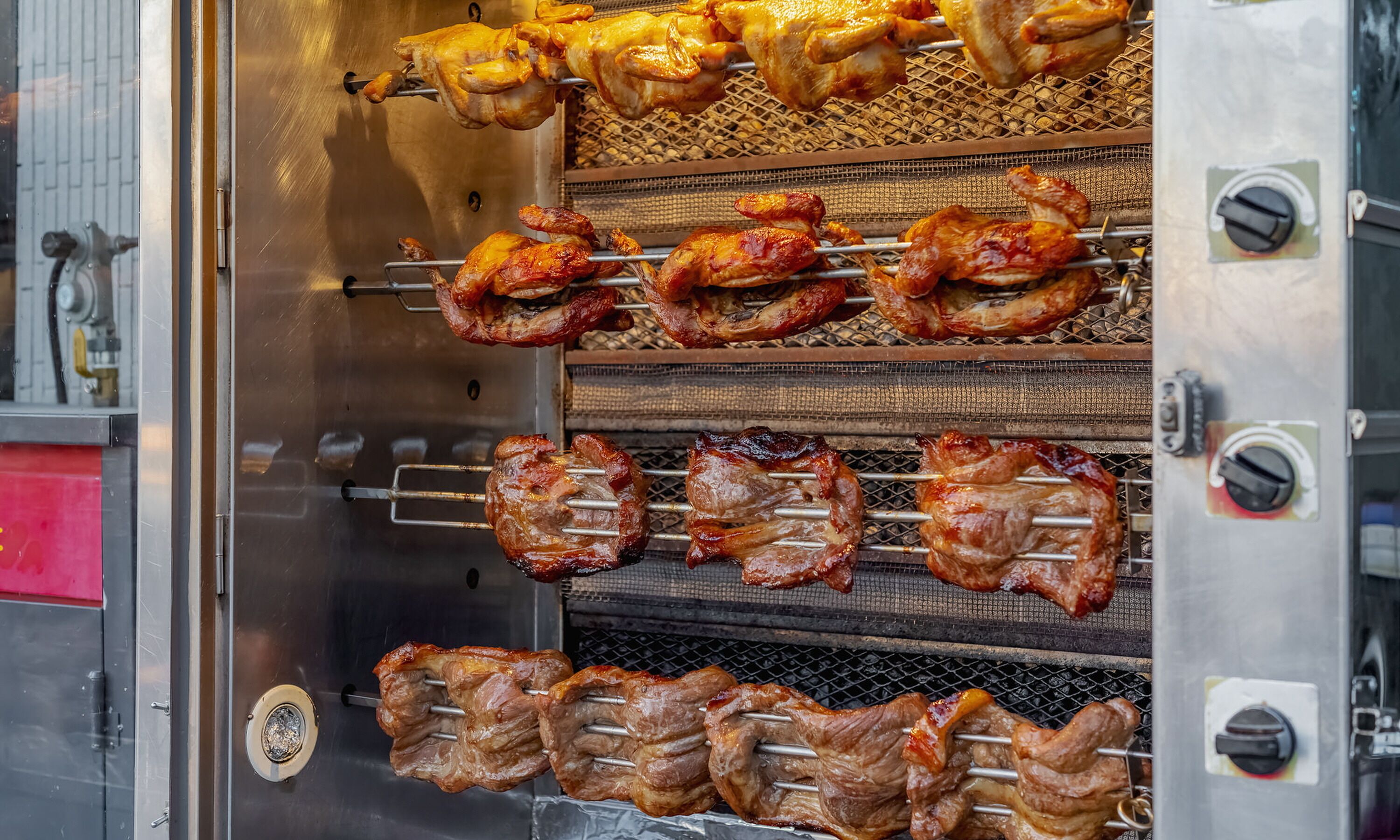 Una cocina comercial con varias estaciones de cocina, incluyendo un asador giratorio y parrillas.
