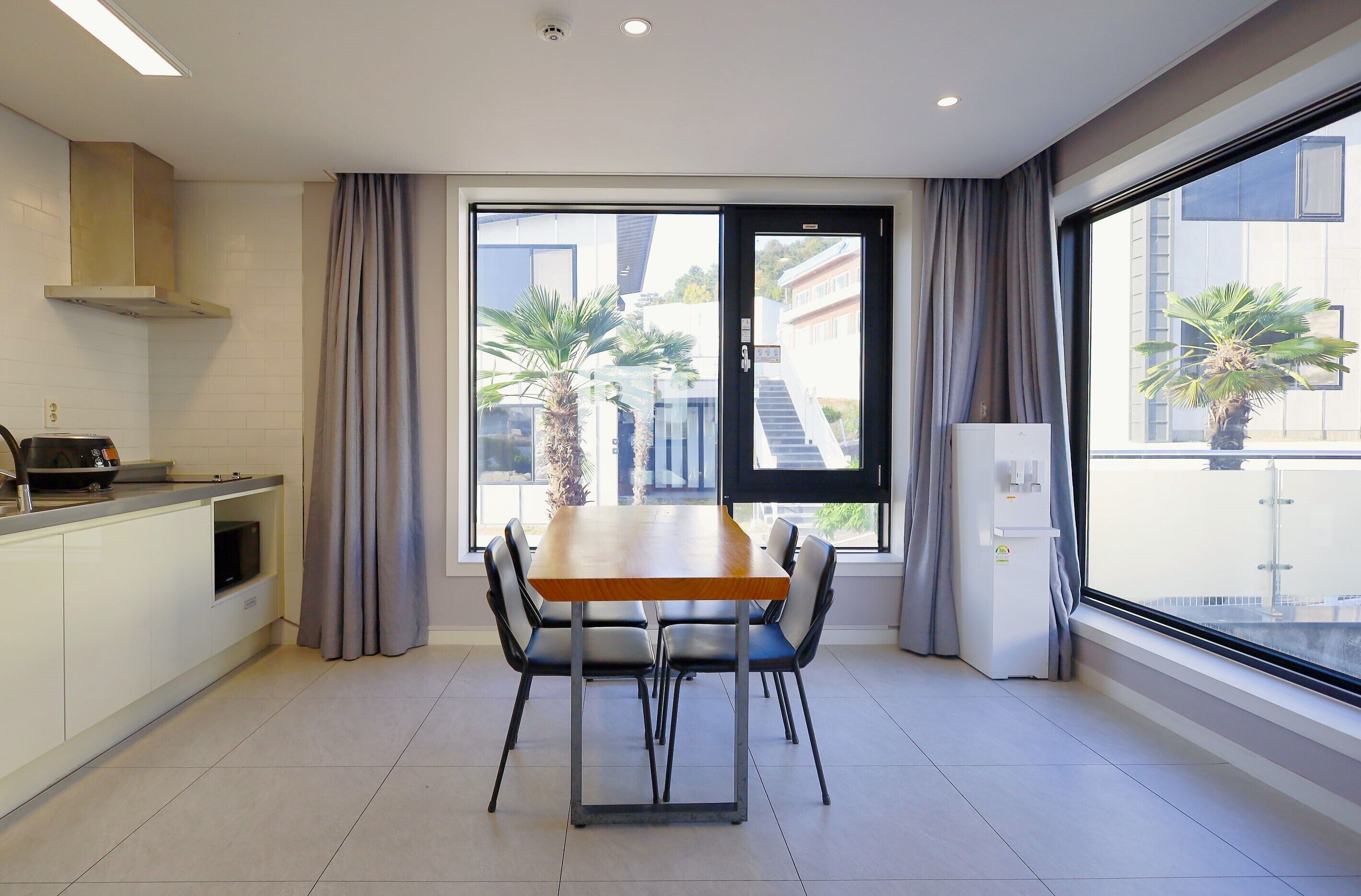 A modern kitchen with a dining table, chairs, and a view of a building outside.