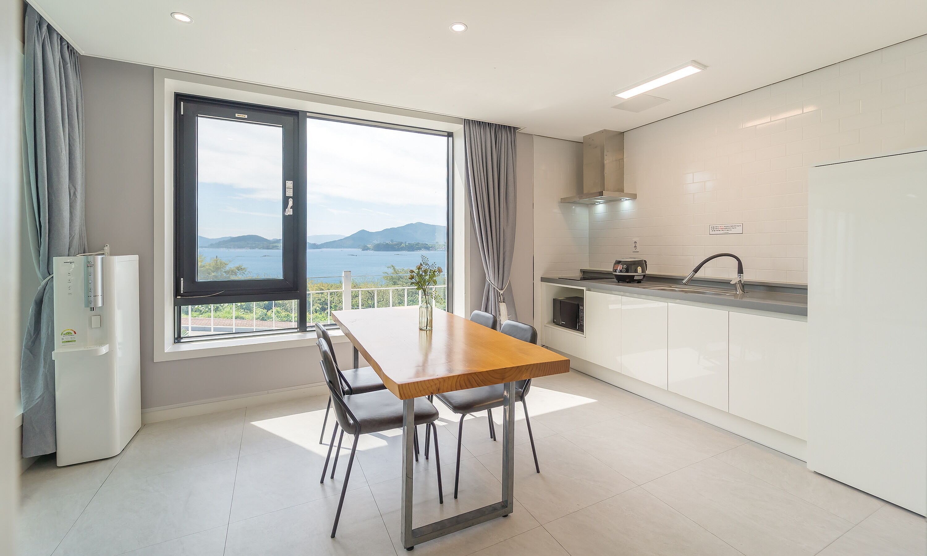 Une cuisine moderne avec un coin repas, de grandes fenêtres et une vue sur la mer.