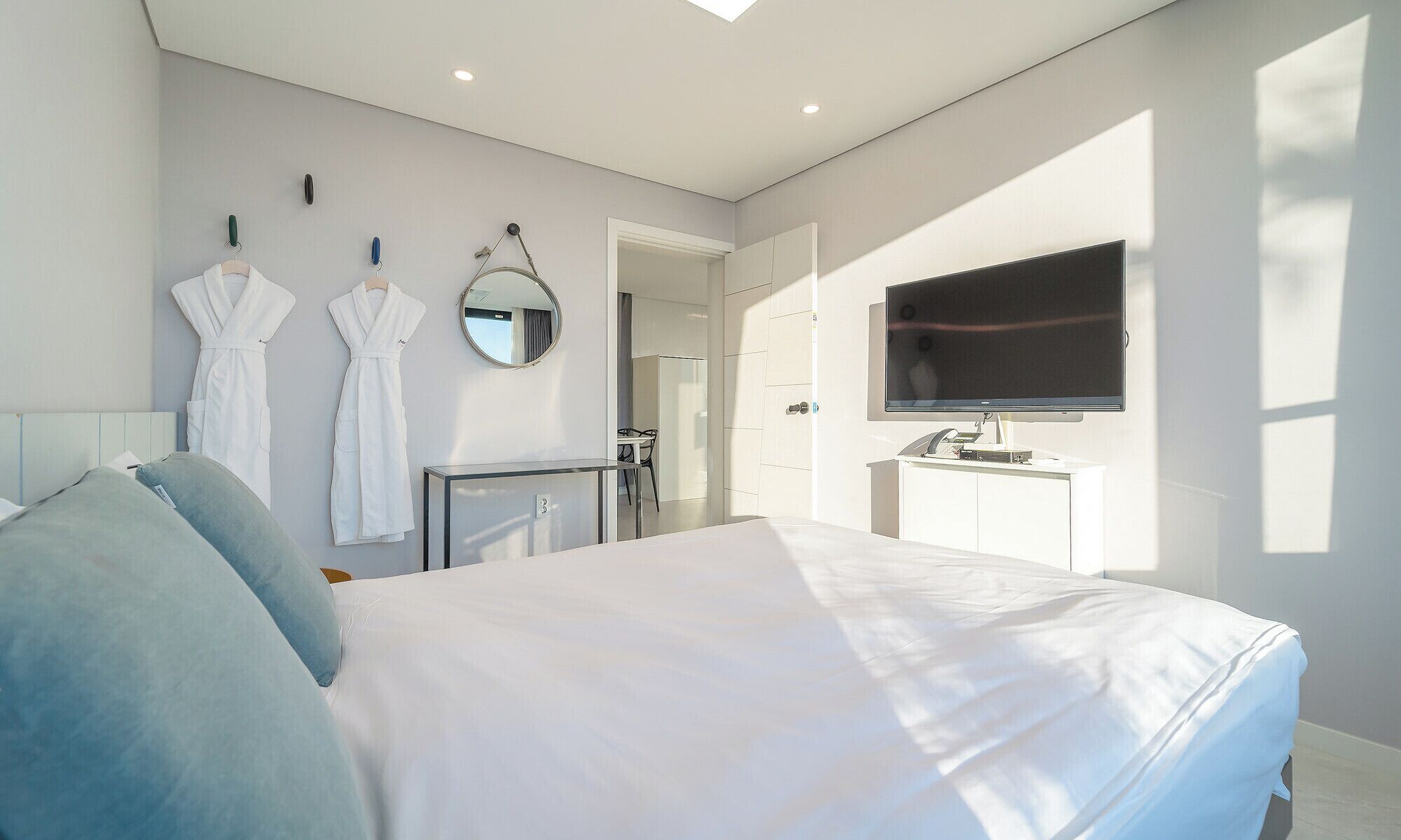 Een moderne hotelkamer met een bed, een televisie, een bureau en een badkamer zichtbaar door een geopende deur.