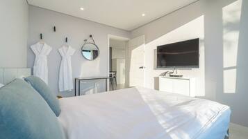 Een moderne hotelkamer met een bed, een televisie, een bureau en een badkamer zichtbaar door een geopende deur.