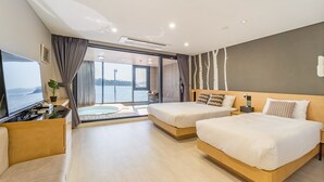 Quarto de hotel com duas camas, televisão, vista para o mar e varanda.