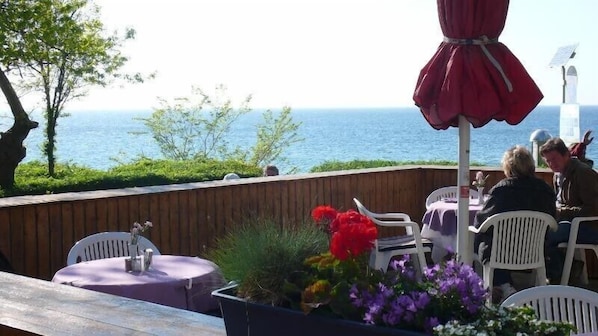 An outdoor seating area with tables and chairs, overlooking a body of water.