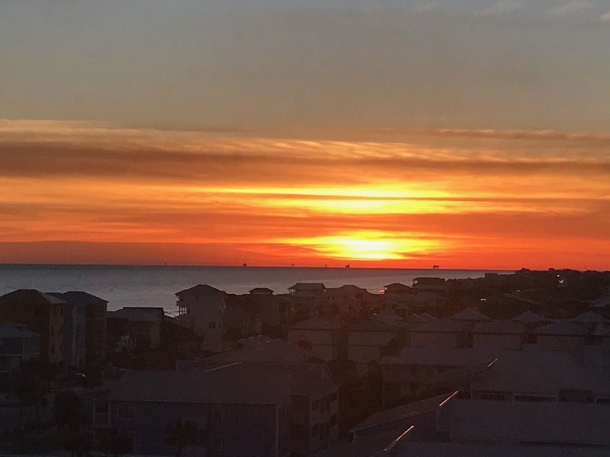 A coastal sunset with buildings silhouetted against the sky.