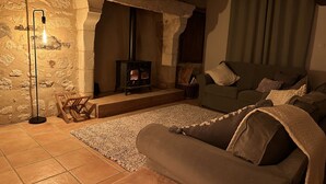 A cozy living room with a stone wall, a fireplace, a sofa, and a floor lamp.