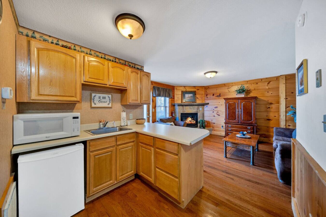 A kitchen with wooden cabinets, a microwave, and a fireplace.