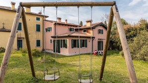 A wooden swing set in a grassy yard with a house in the background. - XV century villa recently restored , located on Colà di Lazise (Colà di Lazise)