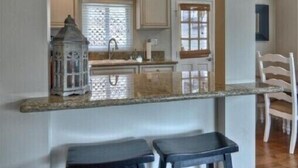 A kitchen with a large fish decoration, two stools, and a window with blinds. - Enjoy Ocean View from Large Private Patio, A/C & Garage (Corona del Mar)