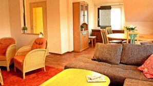 A living room with wicker furniture, a sofa, a dining table with chairs, and a cabinet. - Spacious apartment right on the Fürstenauer castle (Fürstenau)