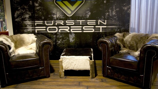 A room with two leather armchairs, a small ottoman, and a backdrop with 'FURSTEN FOREST' logo. - Spacious apartment right on the Fürstenauer castle (Fürstenau)