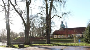 A paved pathway leading to a building with a dome, surrounded by trees and a grassy area. - Spacious apartment right on the Fürstenauer castle (Fürstenau)
