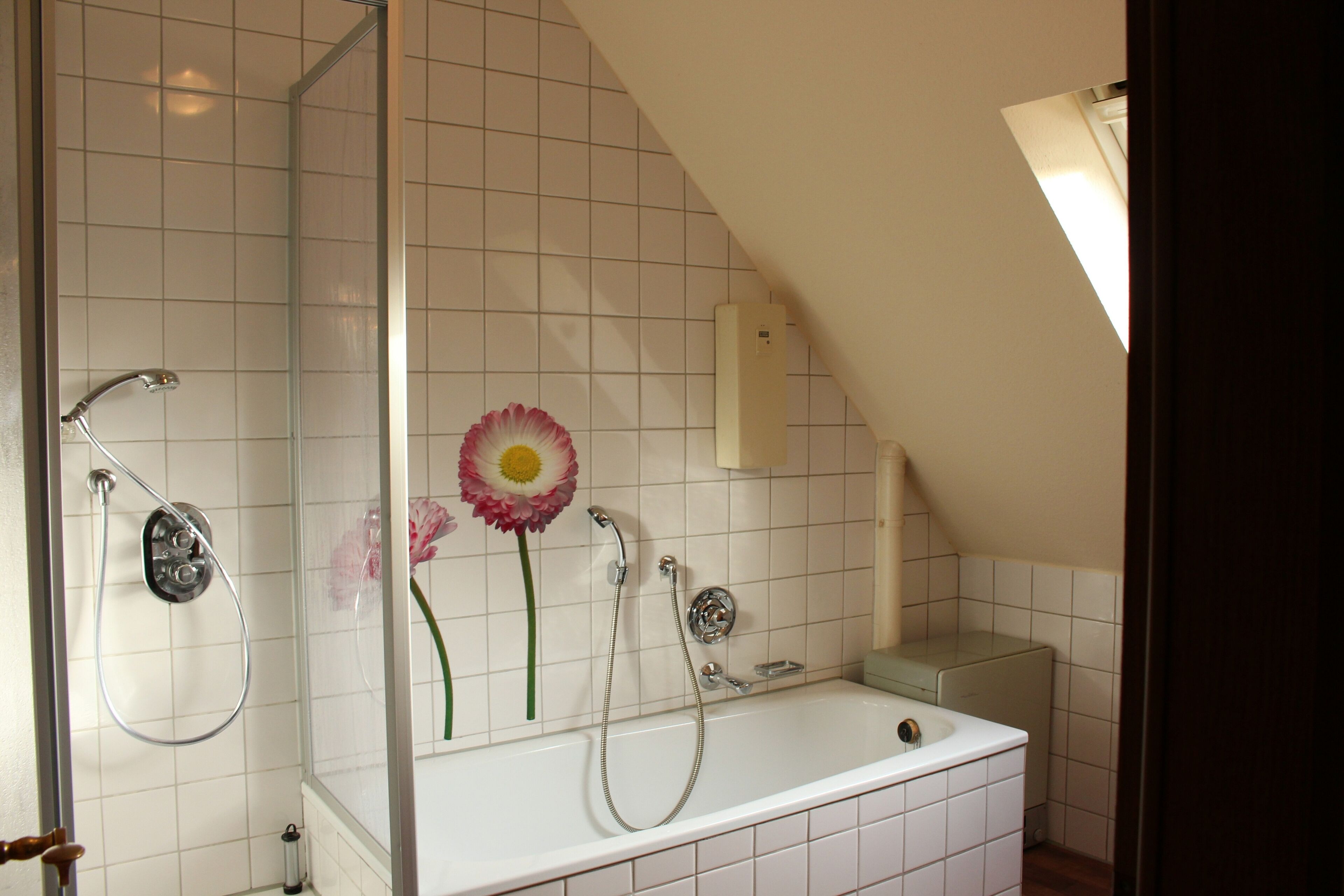 A bathroom with a shower, a bathtub, and a hand dryer.