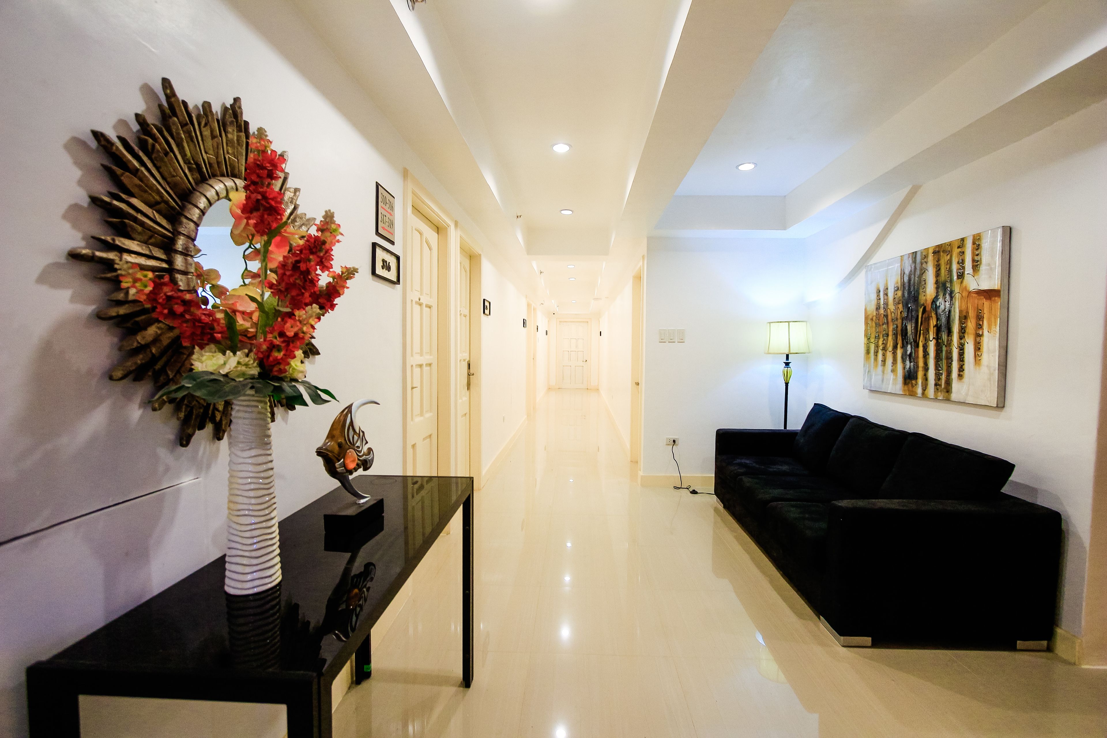 A hallway with a black console table, a mirror, and a black sofa.
