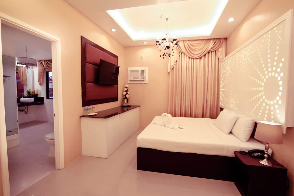 Une chambre d’hôtel moderne équipée d’un grand lit, d’un bureau, d’une télévision et d’un luminaire au plafond.