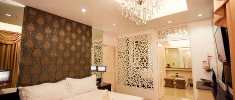 Habitación de hotel luminosa con una cama grande, una araña y un panel decorativo en la pared.