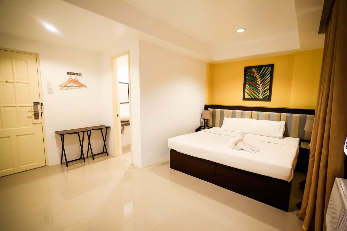 Une chambre d’hôtel avec un lit, une table de chevet et un porte-manteau.