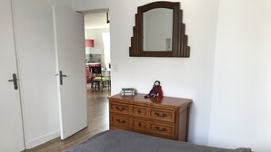 Et soveværelse med seng, kommode, spejl og udsigt til spiseområdet.