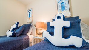 Une chambre à coucher avec un lit, des oreillers, une table de chevet, une lampe et des œuvres d’art murales.