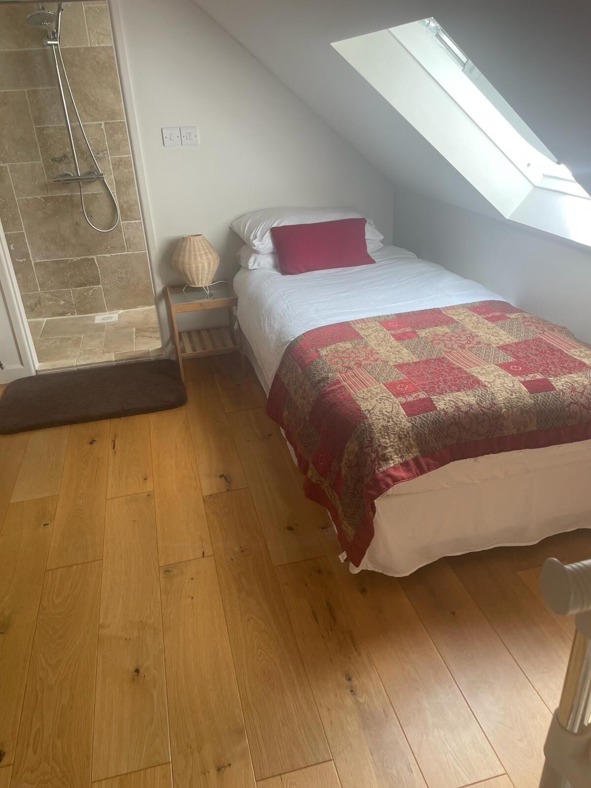 Een slaapkamer met dakraam, douche en houten vloer.