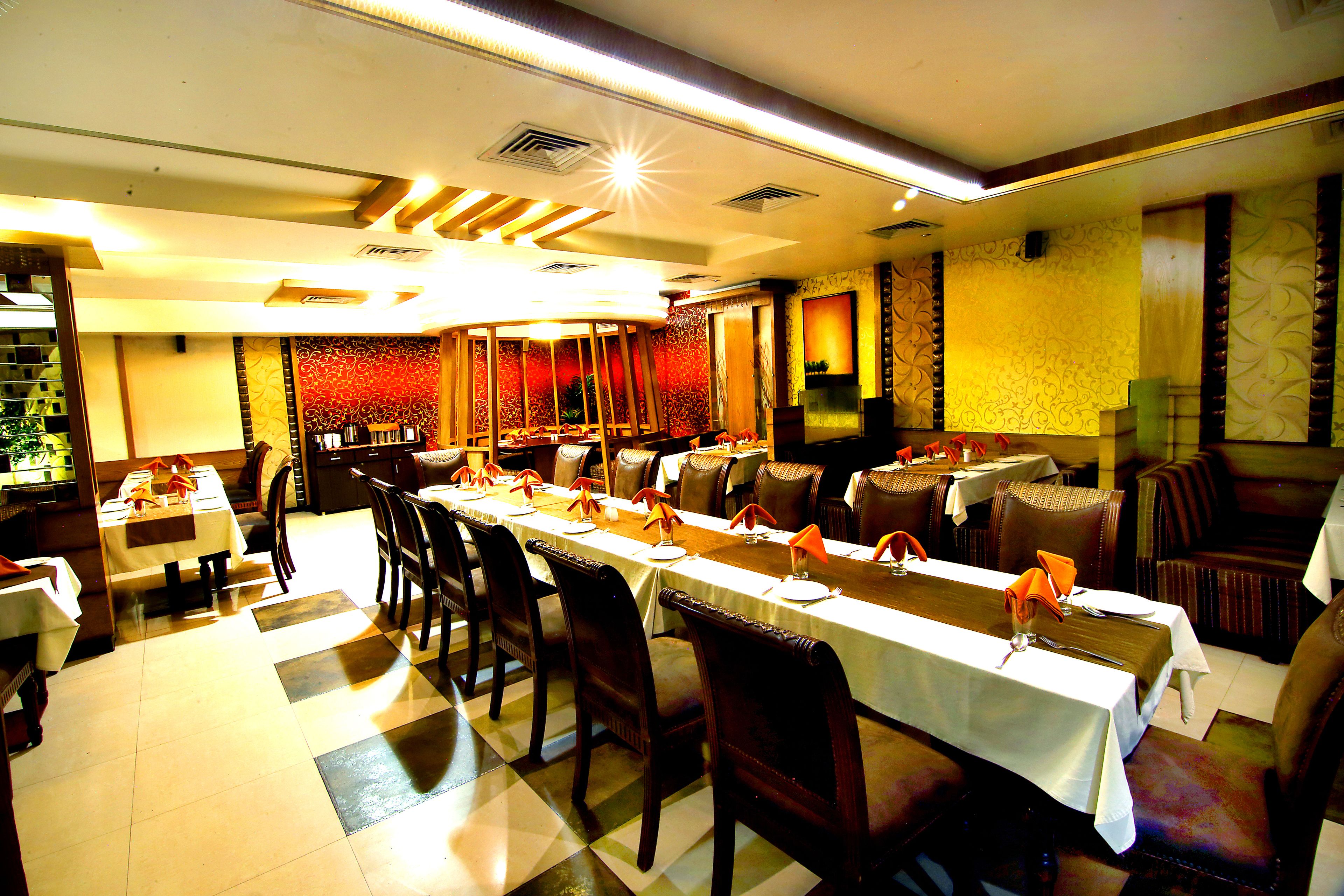 Un restaurante con varias mesas y sillas, piso a cuadros y techo decorativo.