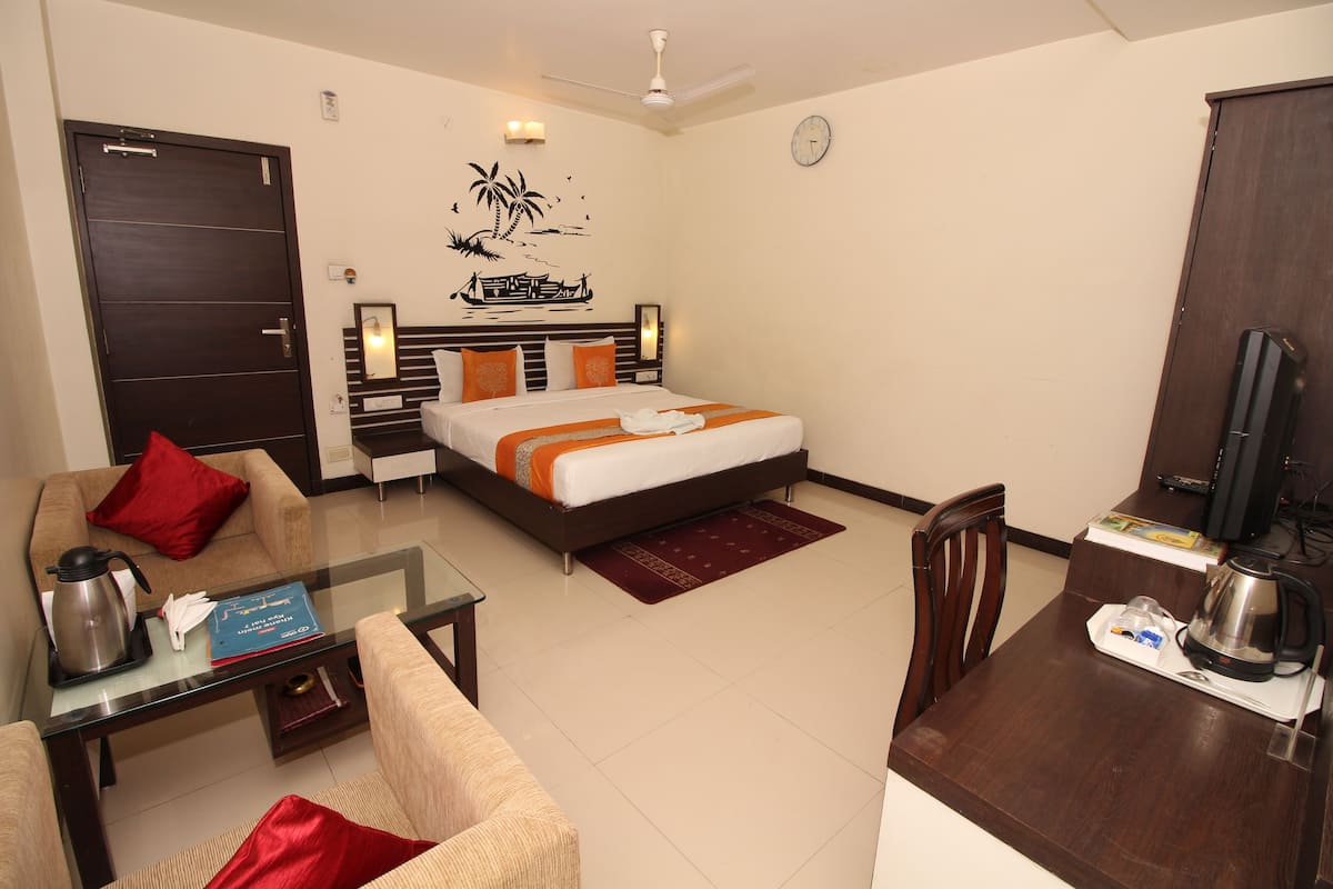 Una habitación de hotel con cama, sofá, mesa de centro, escritorio y televisor.