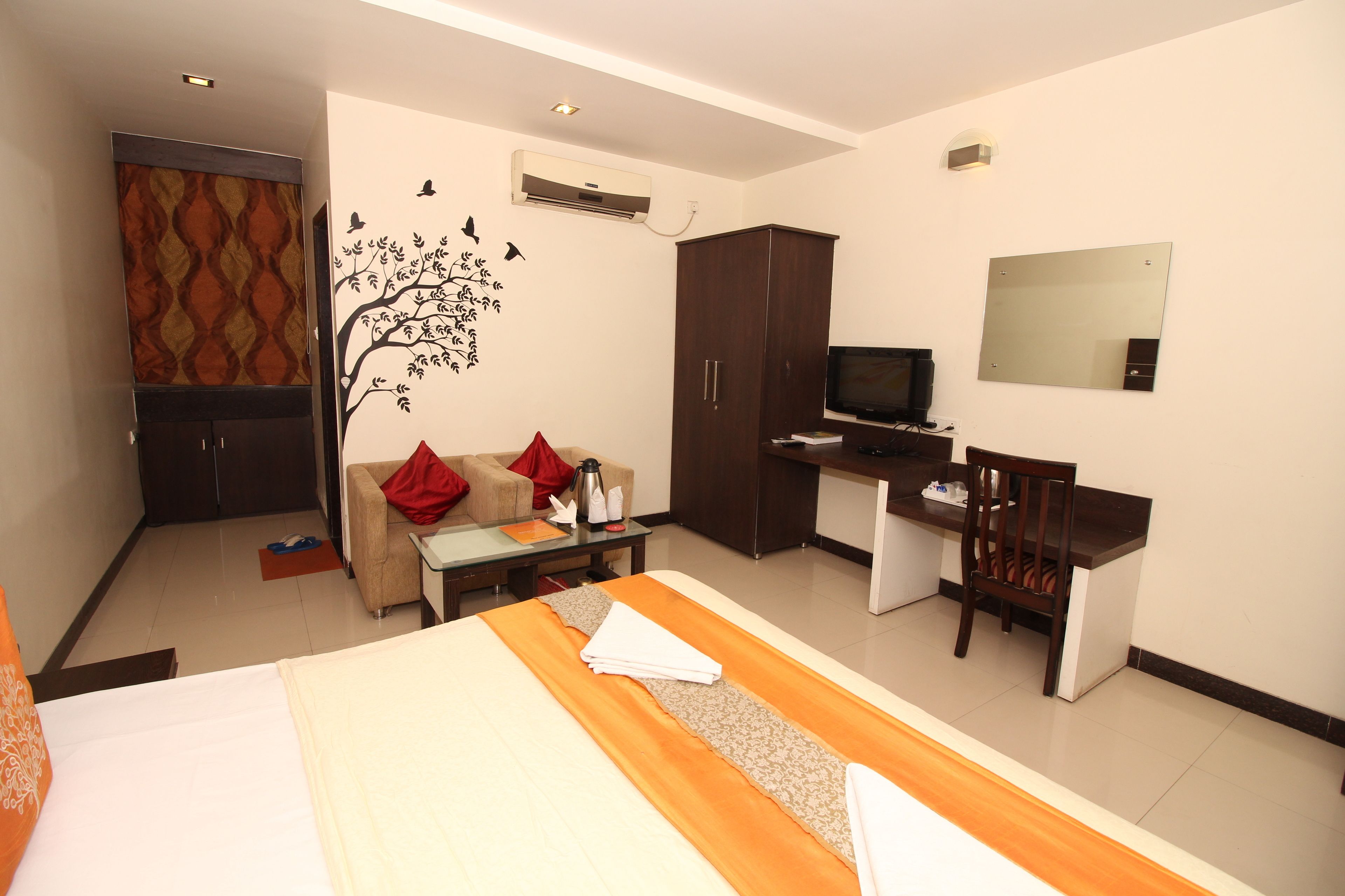 A hotel room with a bed, a desk, a TV, a wardrobe, and a sofa.