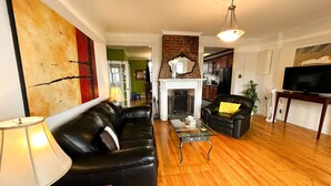 Una sala de estar con chimenea, sofás de cuero negro, una mesa de centro de madera y un mueble para televisor.