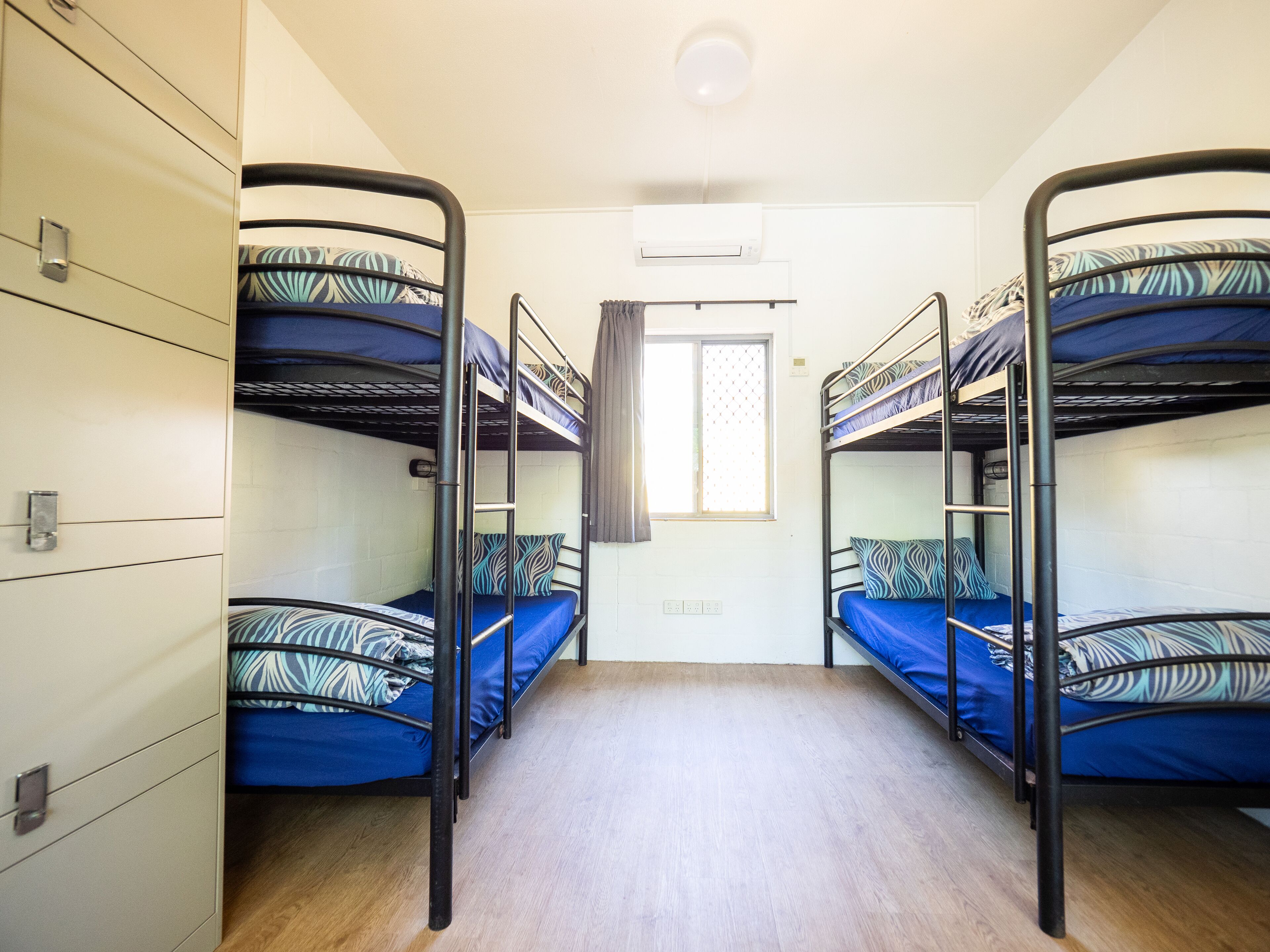 Un dormitorio con literas, una ventana con cortinas y una pared blanca.