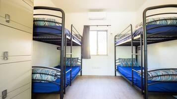 Un dormitorio con literas, una ventana con cortinas y una pared blanca.