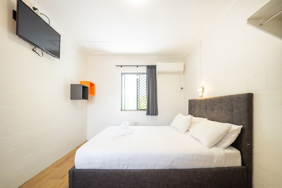 Una camera da letto con un letto, una TV a parete e un condizionatore d'aria.