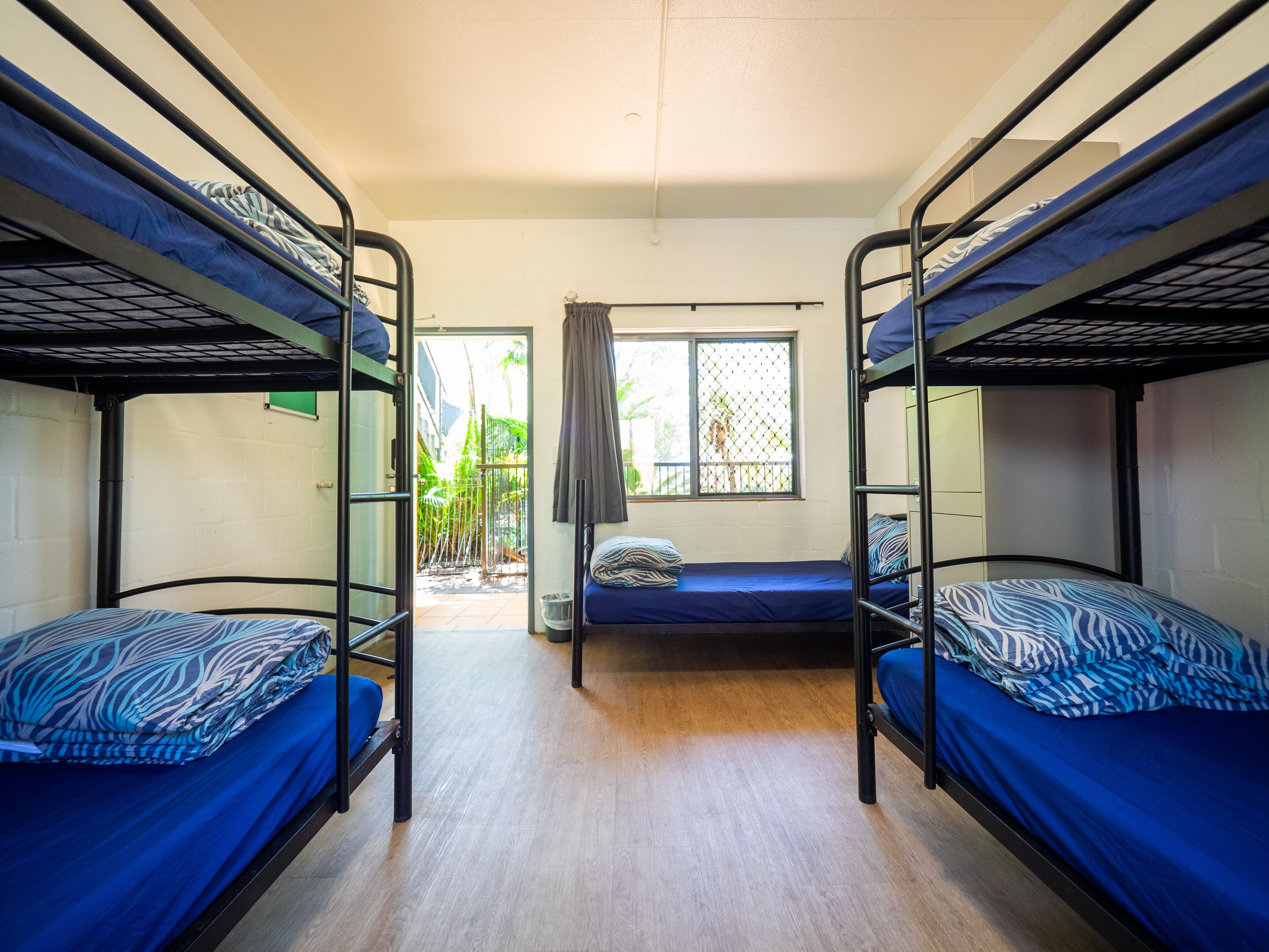 Un dormitorio con literas, una ventana que da a zonas verdes y una puerta que conduce al exterior.