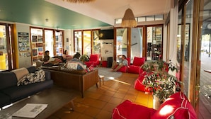 A spacious lobby with a large seating area, a television, and a visible staircase leading to other floors. - YHA Cape Byron (Byron Bay)