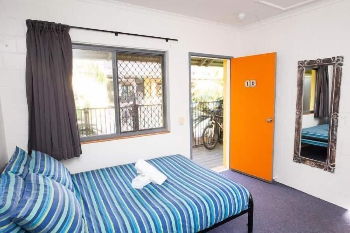 Una camera con un letto singolo, una finestra, una porta e uno specchio.