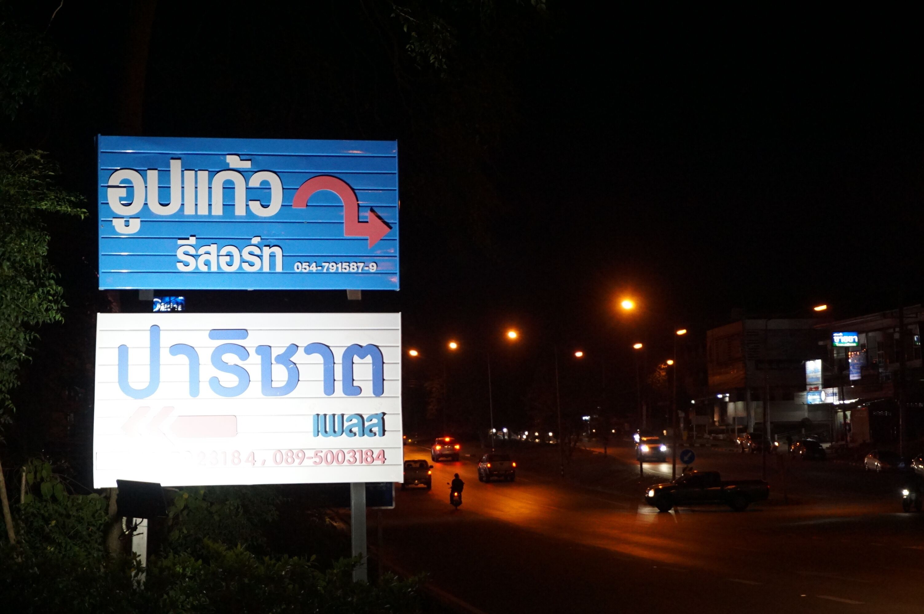 A nighttime street scene with two large billboards.